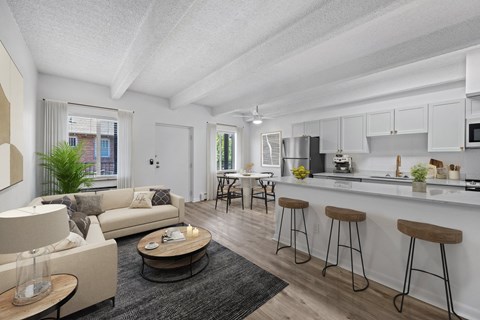 A modern kitchen with white cabinets and a bar area with stools.
